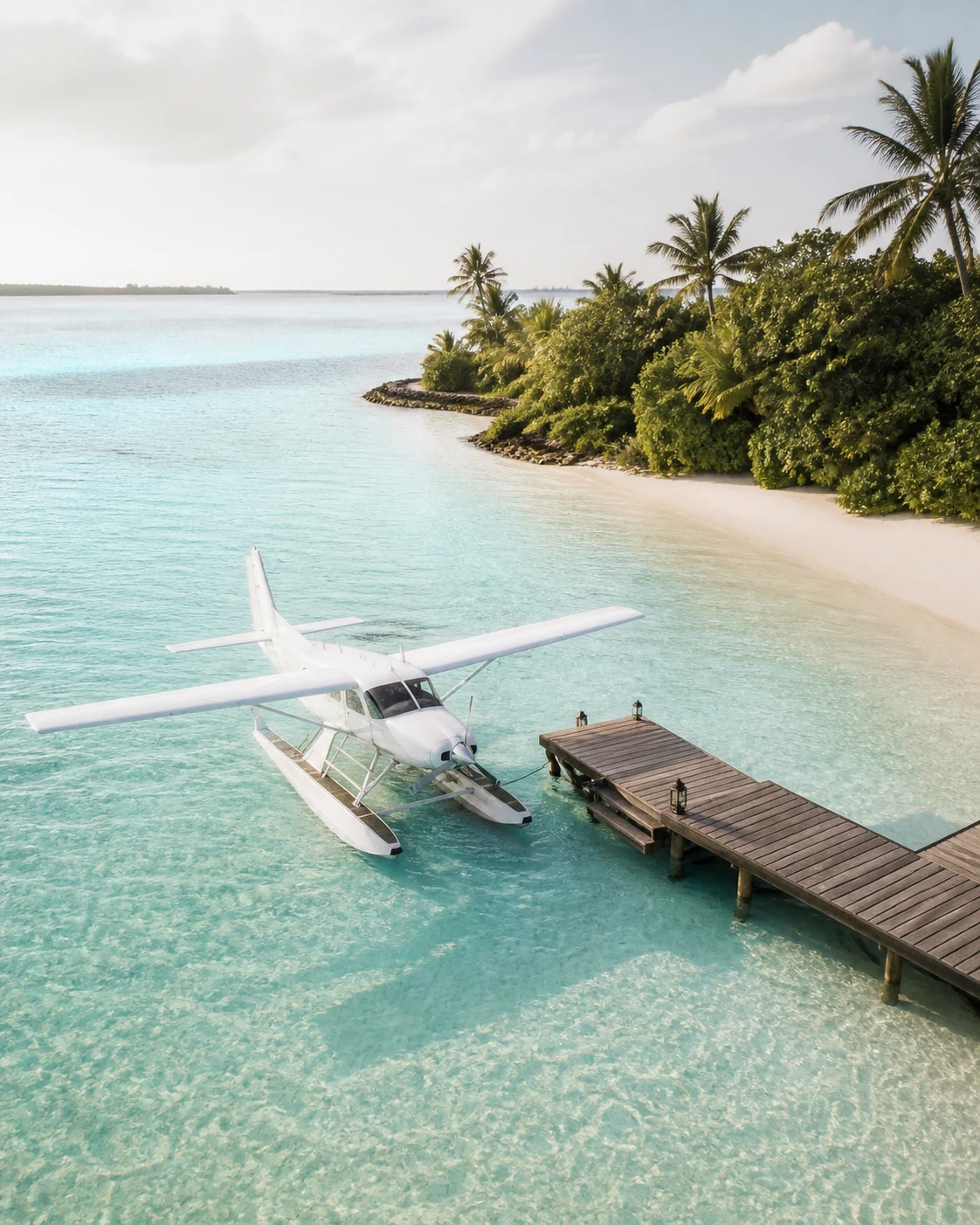 Seaplane beside a wooden jetty in a turquoise Maldives lagoon